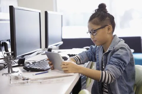 Pre-adolescent girl programming robotics at digital tablet in classroom 스톡 사진