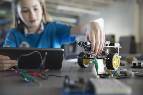 Pre-adolescent girl programming robotics at digital tablet in classroom 스톡 사진