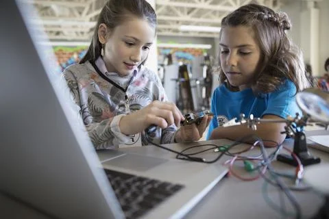 Pre-adolescent girls assembling electronics at laptop in classroom Stock Photos