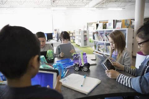 Pre-adolescent students programming electronics at digital tablets in library 写真素材