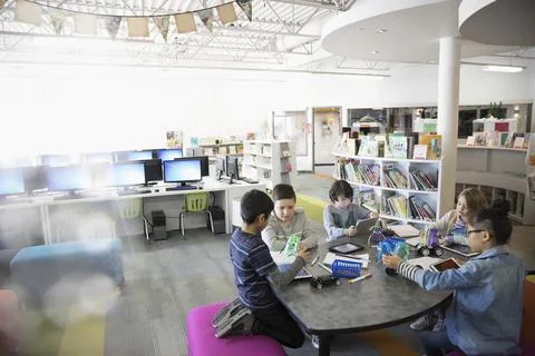 Pre-adolescent students programming electronics at digital tablets in library Stock Photos