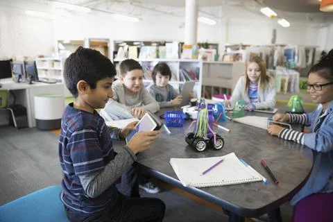 Pre-adolescent students programming robotics at digital tablets in library 스톡 사진