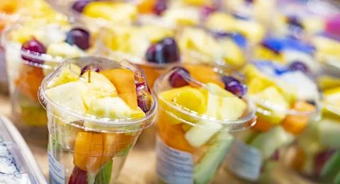 Pre-packaged fruit salads displayed in a commercial refrigerator. Stock Photos