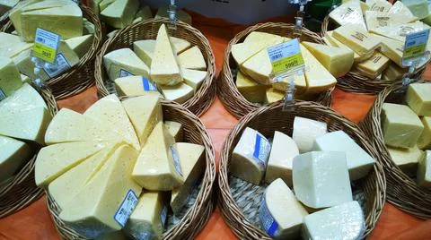 Pre-packaged triangular pieces of cheese in wicker baskets in supermarket Stock Photos