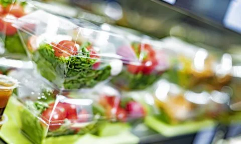 Pre-packaged vegetable salads displayed in a commercial refrigerator Stock Photos