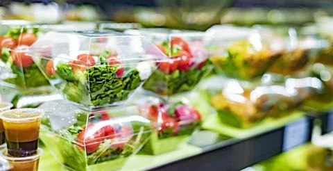 Pre-packaged vegetable salads displayed in a commercial refrigerator Stock Photos