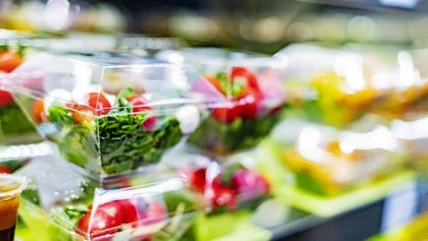 Pre-packaged vegetable salads displayed in a commercial refrigerator Stock Photos