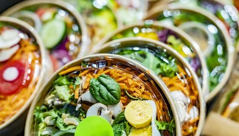 Pre-packaged vegetable salads displayed in a commercial refrigerator Stock Photos