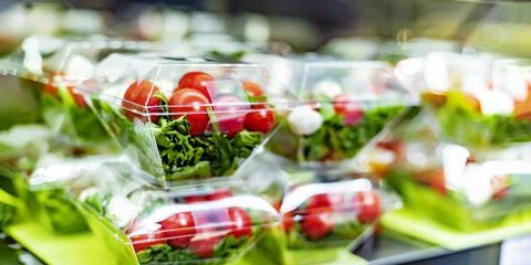 Pre-packaged vegetable salads displayed in a commercial refrigerator Stock Photos