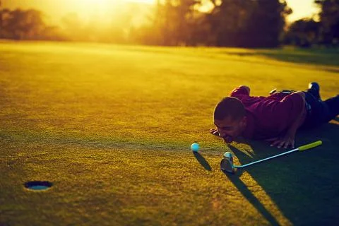 Pre putt prep. a young man eyeing up the putt during a round of golf. Stock Photos