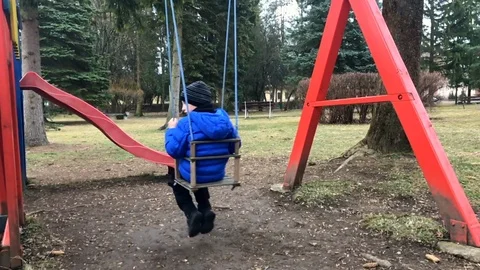 Pre-school age boy on swing in the park from behind Stock Footage 104218632