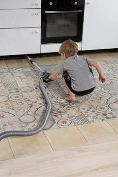 Pre-school boy does homework, vacuums floor. Help parents at home. Stock Photos