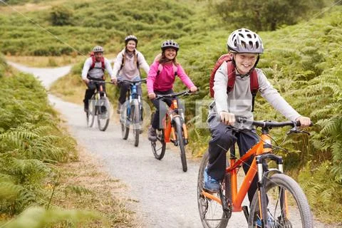 Pre-teen boy riding mountain bike with his sister and parents during a family Stock Photos