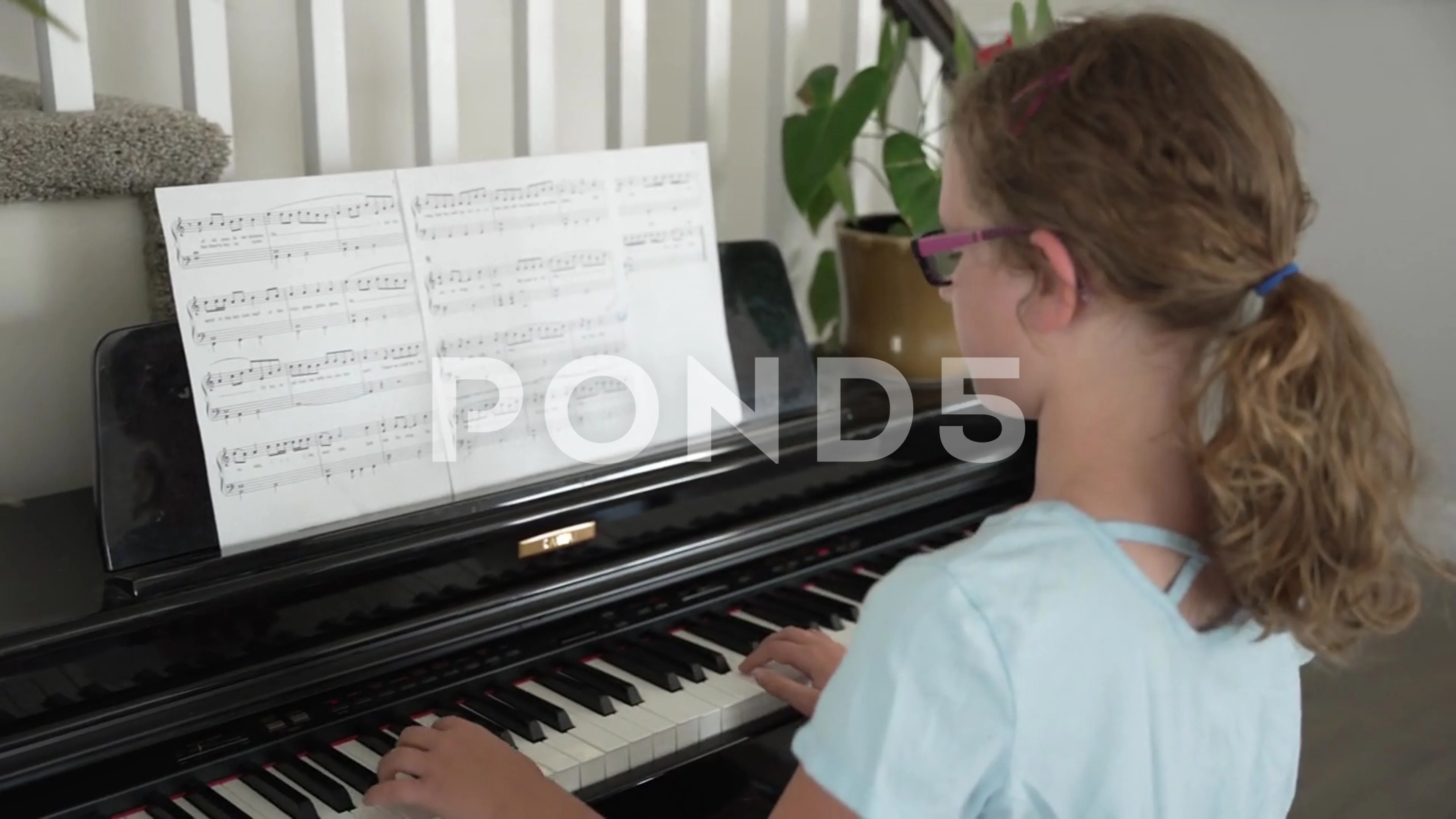 Pre-teen girl sits at a piano in home and practices her music learning new part