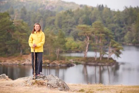 A pre-teen girl standing on a rock holding a stick, smiling to camera, lakesi Stock Photos