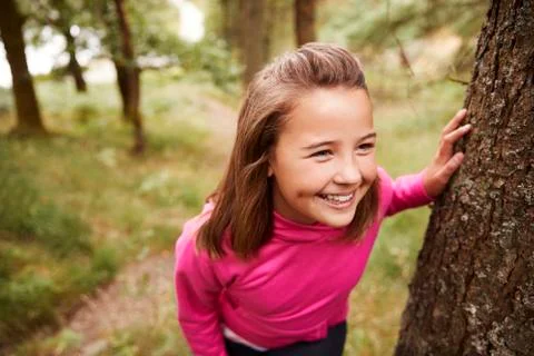 Pre-teen girl taking a break leaning on tree during a hike in a forest, eleva Stock Photos