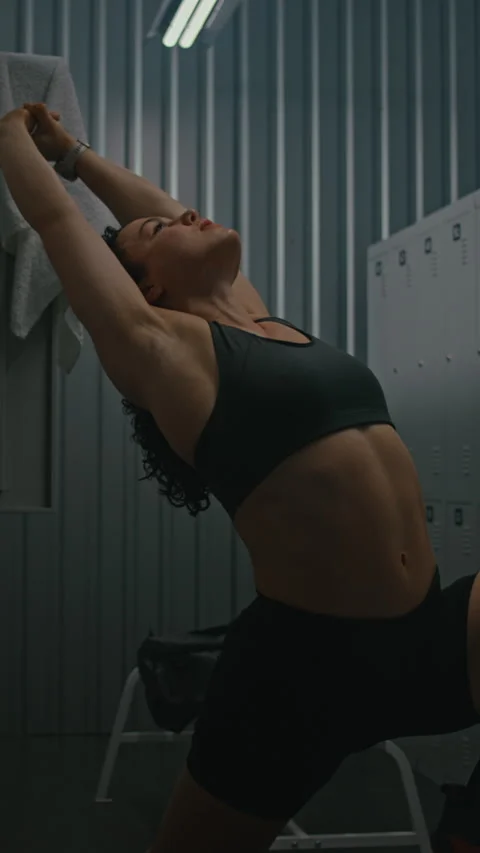 Pre workout Stretching Routine, Athletic Woman in Moody Locker Room Stock Footage 335394081
