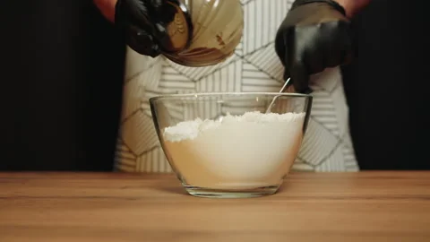 Precise actions as man measures and transfers yeast to flour in glass bowl Video stock 330536549
