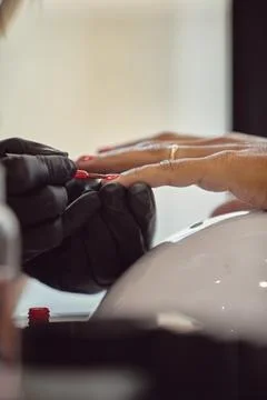 Precise application of red nail polish at a nail salon. Stock Photos
