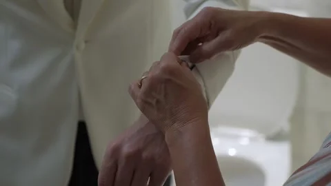 Precise Capture Of Mother Gently Attaching Cufflink On Groom During Heartfelt Stock Footage 323777001