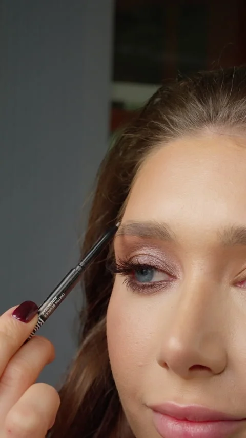 Precise eyebrow makeup application showcasing detailed grooming technique with Stock Footage 304352172