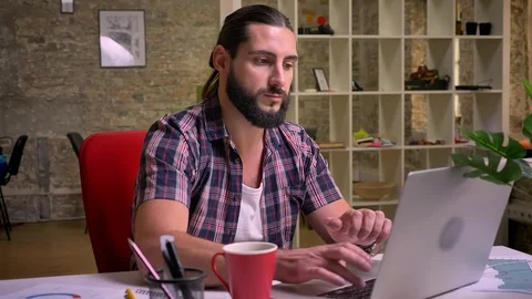 Precise look at the screen of caucasian nice bearded male, casual style, sitting Video stock 97891688
