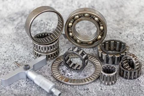 Precision depth micrometer gauge and assorted roller bearings lying on work.. Stock Photos