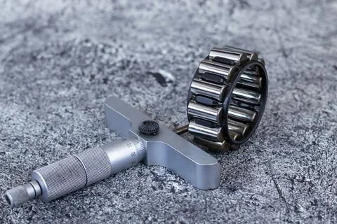 Precision depth micrometer gauge lying beside cylindrical roller bearing on.. Stock-Fotos