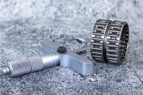 Precision depth micrometer gauge lying near needle roller bearings on concr.. Photos
