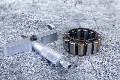 Precision depth micrometer gauge lying beside cylindrical roller bearing on.. Photos