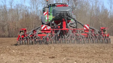 Precision drill seeding by green tractor with red seed drill in spring Video stock 337583659