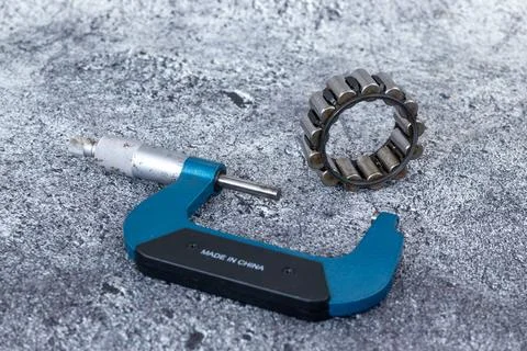 Precision micrometer caliper lying beside cylindrical roller bearing on tex.. Stock-Fotos