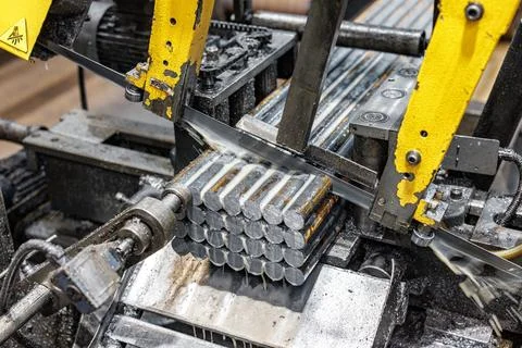 Precision in Motion: A metal cutting machine slices through steel rods, sho.. Foto stock