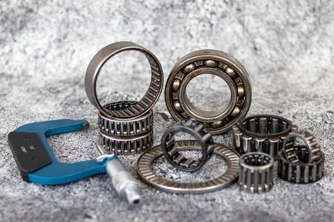 Precision outside micrometer caliper and assorted roller bearings lying on .. Stock Photos
