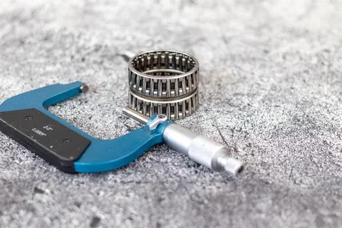 Precision outside micrometer caliper lying near stacked needle roller beari.. Stock Photos