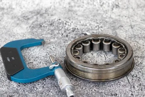 Precision outside micrometer caliper lying beside cylindrical roller bearin.. Stock-Fotos