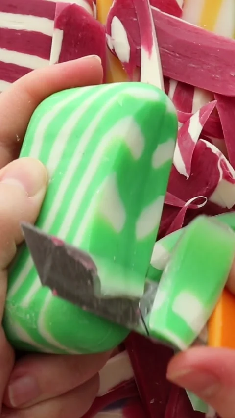 Precision slicing of a green-striped soap bar with smooth textures and detailed Stock Footage 313753356