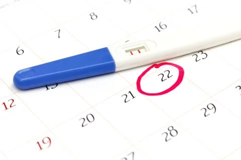 Pregnancy test with positive result lying on calendar Stock Photos