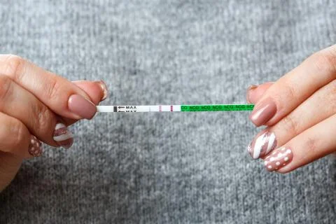 A pregnancy test with two strips in the hands of a young woman . pregnancy Stock Photos