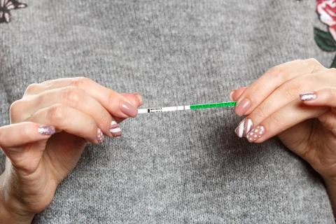 A pregnancy test with two strips in the hands of a young woman . pregnancy Stock Photos