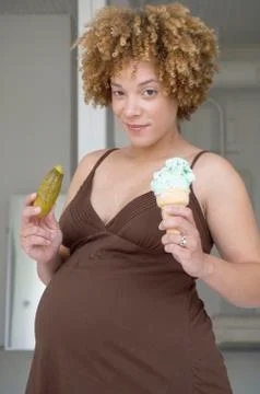 Pregnant African woman holding pickle and ice cream Stock Photos