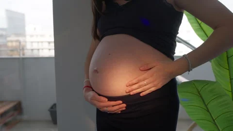 Pregnant belly held gently by two hands with bracelet and ring Stock-Footage 335511139