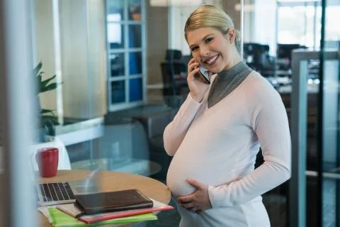 Pregnant businesswoman talking on mobile phone in office Stock Photos