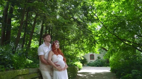 Pregnant couple hugging at summer park. Romantic couple relax outdoor Stock Footage