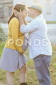 Pregnant couple kissing in sunny field Stock Photos