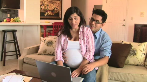 Pregnant couple using laptop Видео 828362