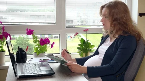 Pregnant freelancer woman making notes in notebook working at home office Stock Footage