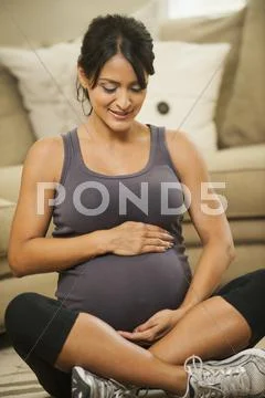 Pregnant Hispanic woman holding her belly Stock-Fotos
