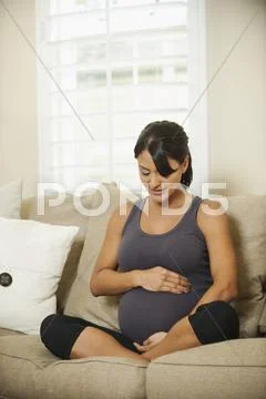 Pregnant Hispanic woman holding her belly Stock Photos
