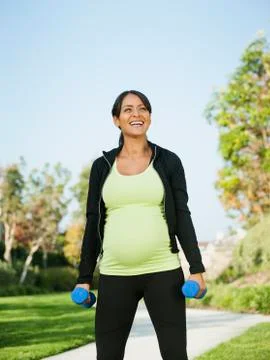 Pregnant Hispanic woman lifting weights outdoors Stock Photos